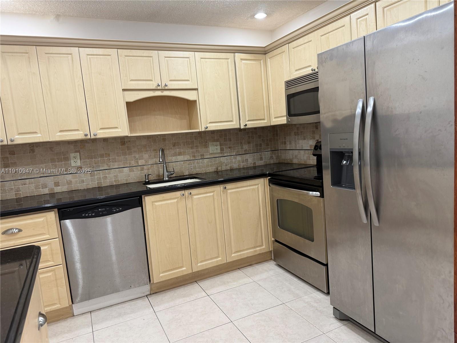 12810 Southwest 43rd Drive, Unit 115B Miami, FL 33175 - Photo 2 of 22 a kitchen with stainless steel appliances granite countertop a refrigerator sink and cabinets