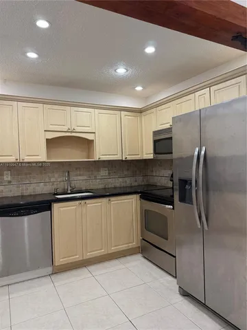 a kitchen with granite countertop a refrigerator and a sink