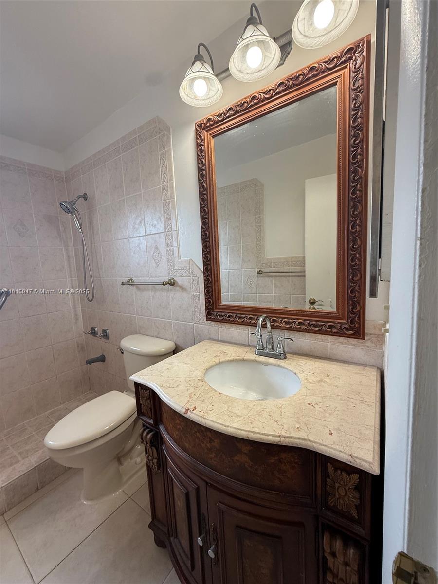 12810 Southwest 43rd Drive, Unit 115B Miami, FL 33175 - Photo 8 of 22 a bathroom with a granite countertop toilet a sink and a mirror