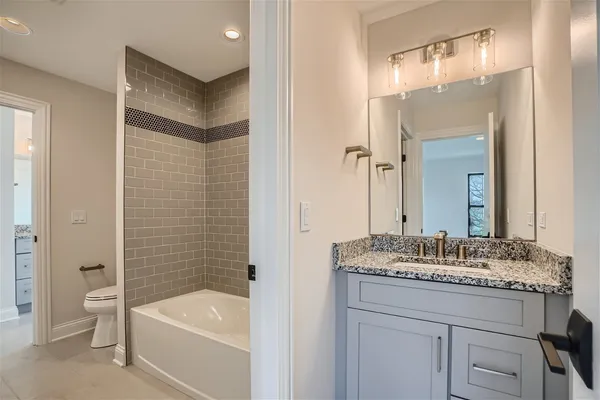 a bathroom with a granite countertop tub sink and mirror