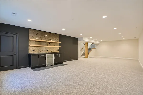 a view of an empty room with kitchen and window