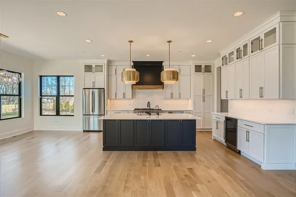 a large kitchen with stainless steel appliances a large counter top a stove and a refrigerator