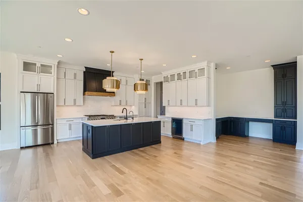 a large kitchen with stainless steel appliances a large counter top a stove a refrigerator and a sink