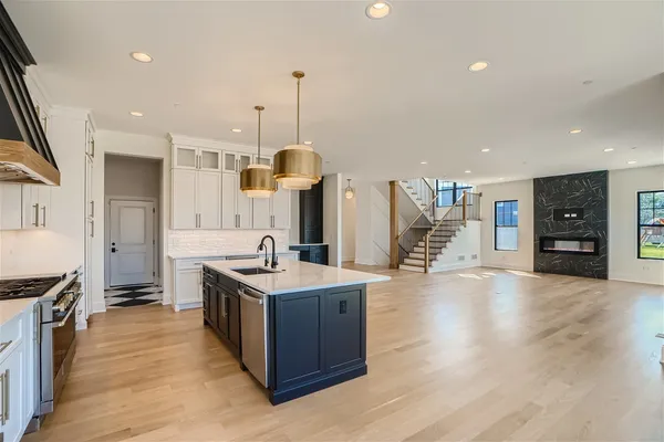 a kitchen with stainless steel appliances granite countertop a sink a stove and a wooden floors