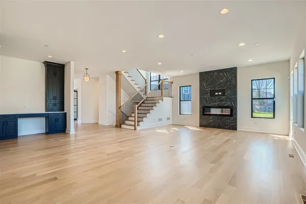 a view of an empty room with wooden floor fireplace and windows