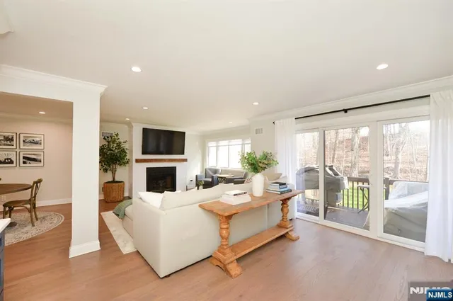a living room with fireplace furniture large windows and a flat screen tv