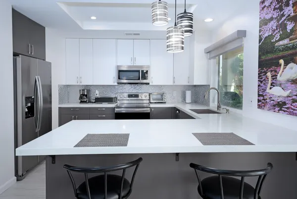 a kitchen with stainless steel appliances a table chairs microwave and refrigerator