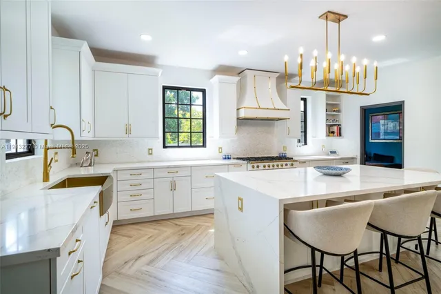 a kitchen with kitchen island granite countertop a sink stove a refrigerator and a dining table with wooden floor