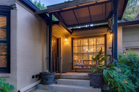 a front view of a house with a floor to ceiling window and potted plants