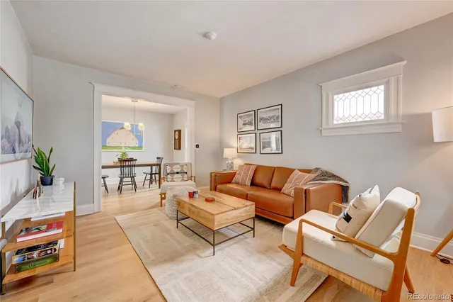 a living room with furniture a wooden floor and a potted plant