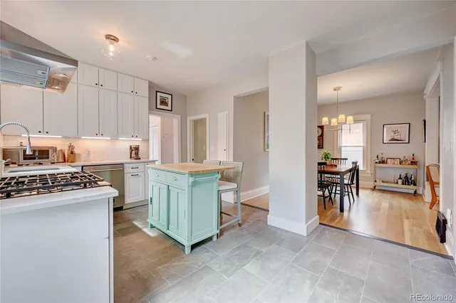 a kitchen with a stove a refrigerator and chairs
