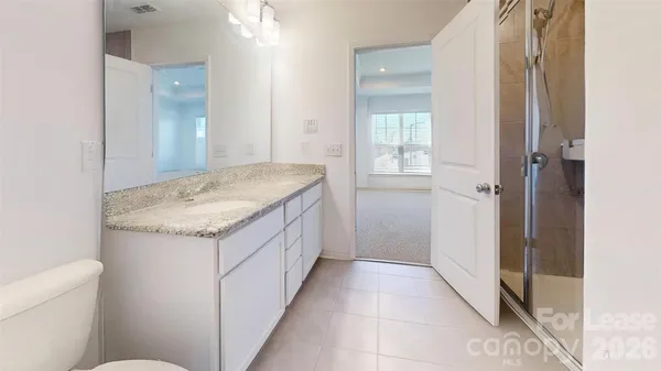 a bathroom with a granite countertop sink a toilet and shower