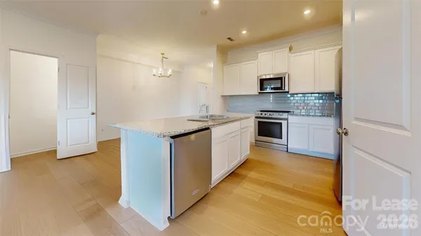 a kitchen with stainless steel appliances granite countertop a stove top oven a sink and a refrigerator