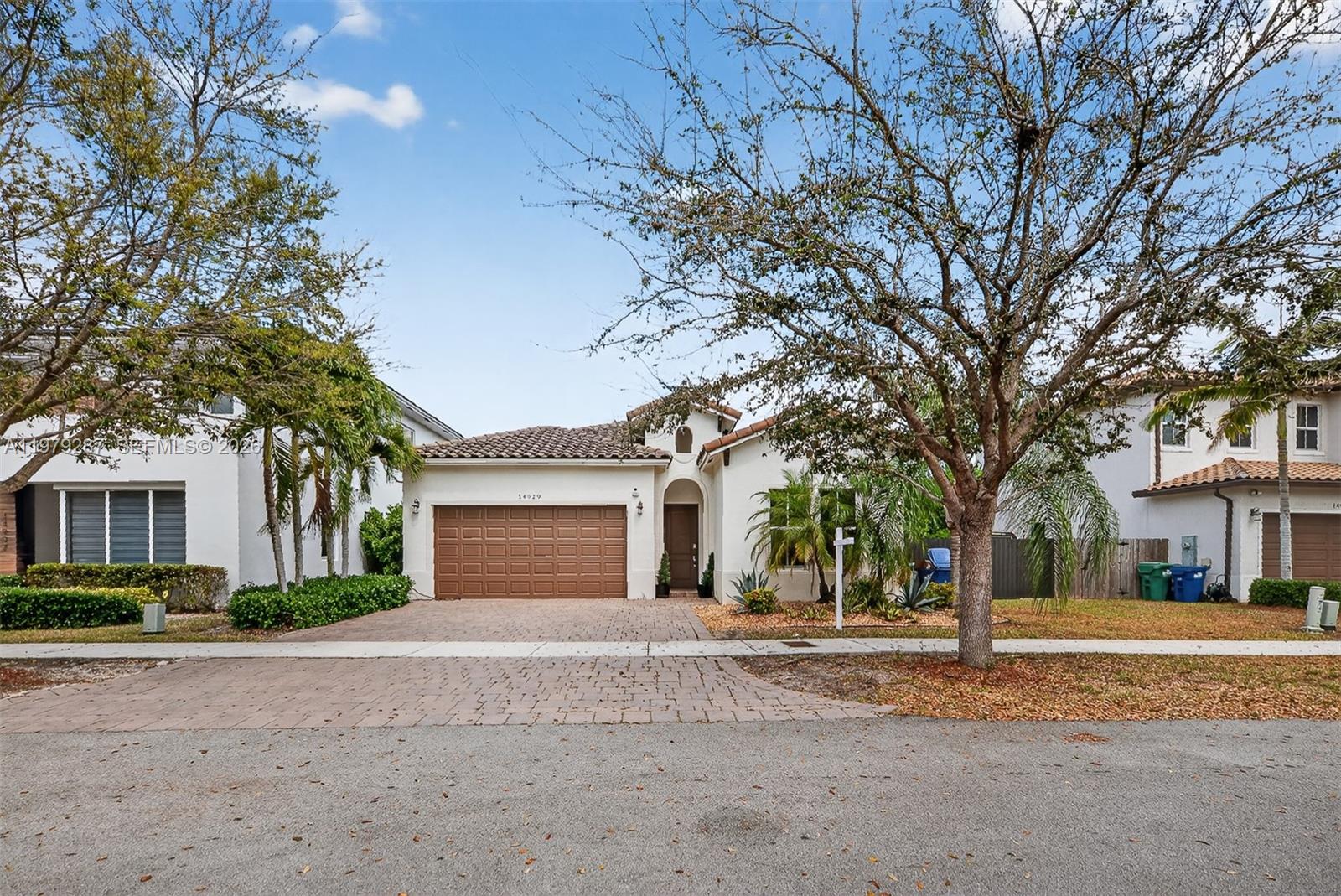 14929 Southwest 176th Terrace Miami, FL 33187 - Photo 2 of 40 a front view of a house with a yard and garage