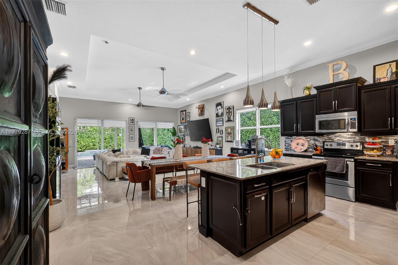 14929 Southwest 176th Terrace Miami, FL 33187 - Photo 38 of 40 a kitchen with kitchen island granite countertop a stove top oven a sink dishwasher a dining table and chairs with wooden floor