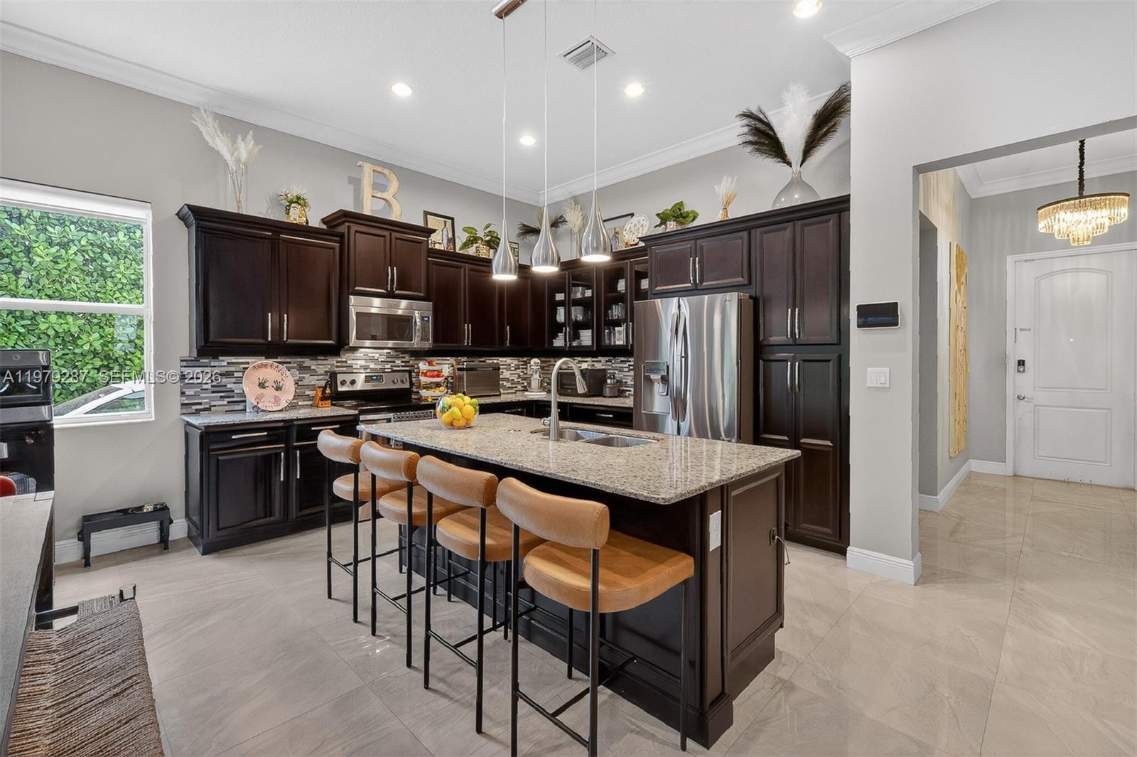 14929 Southwest 176th Terrace Miami, FL 33187 - Photo 39 of 40 a kitchen with stainless steel appliances kitchen island granite countertop a refrigerator a stove a sink a dining table and chairs