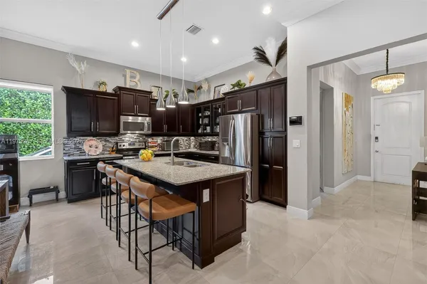 a kitchen with stainless steel appliances kitchen island granite countertop a refrigerator a stove a sink and a dining table with garden view
