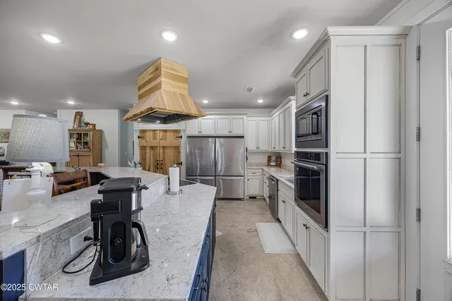 a kitchen with stainless steel appliances kitchen island granite countertop a refrigerator and a stove top oven