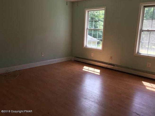 1090 Milford Road Dingmans Ferry, PA 18328 - Photo 10 of 13 an empty room with wooden floor and windows
