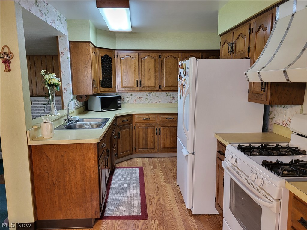 6465 Stoney Ridge Road North Ridgeville, OH 44039 - Photo 8 of 17 Kitchen featuring sink, white range with gas cooktop, custom exhaust hood, and light hardwood / wood-style flooring