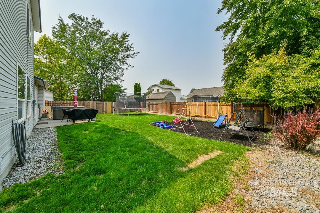 805 Bison Way Caldwell, ID 83607 - Photo 37 of 45 Expansive backyard featuring a large grass lawn, perimeter wood fencing, mature trees, and a concrete patio