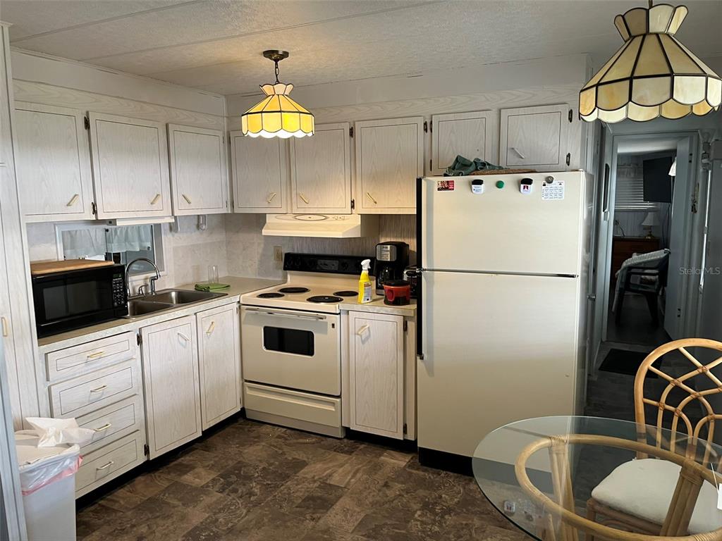 1040 Main Street, Unit 192 Dunedin, FL 34698 - Photo 12 of 15 a kitchen with granite countertop a sink a refrigerator a stove a washer and dryer