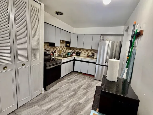 a kitchen with stainless steel appliances a refrigerator and wooden floor