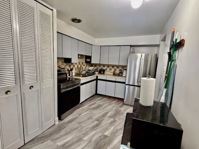 a kitchen with stainless steel appliances granite countertop a refrigerator a stove and a sink