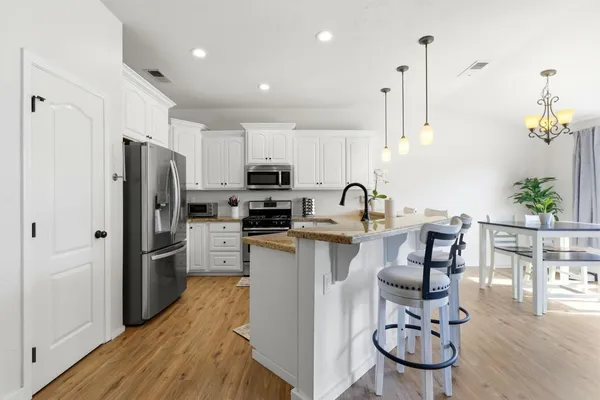 a kitchen with granite countertop a sink stainless steel appliances and white cabinets