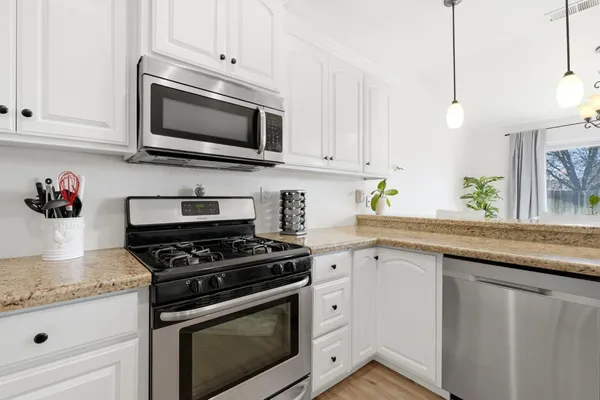 a kitchen with granite countertop white cabinets stainless steel appliances and sink