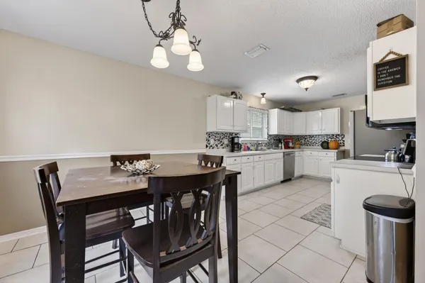 a kitchen with a dining table chairs and refrigerator