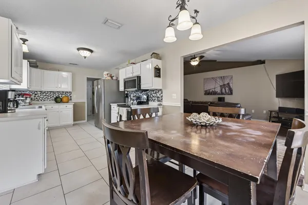 a kitchen with stainless steel appliances granite countertop a stove refrigerator a sink dishwasher a dining table and chairs with wooden floor