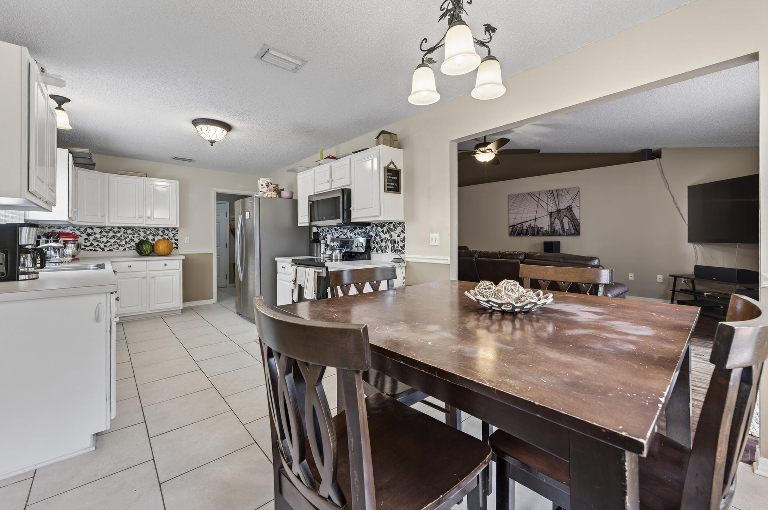 4717 Whitewater Lane Crestview, FL 32539 - Photo 15 of 55 a kitchen with stainless steel appliances granite countertop a stove refrigerator a sink dishwasher a dining table and chairs with wooden floor