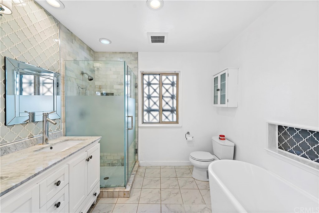 520 Cliff Drive, Unit 303 Laguna Beach, CA 92651 - Photo 22 of 46 a spacious bathroom with a granite countertop toilet a sink and a mirror