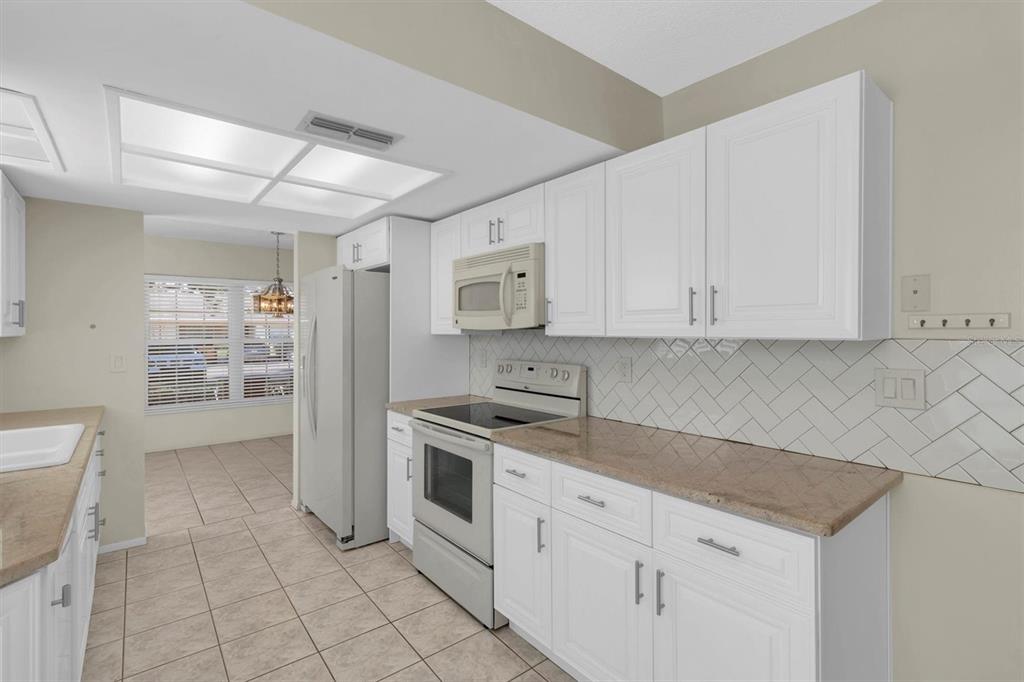 4814 Grist Mill Circle New Port Richey, FL 34655 - Photo 12 of 63 a kitchen with granite countertop white cabinets and stainless steel appliances