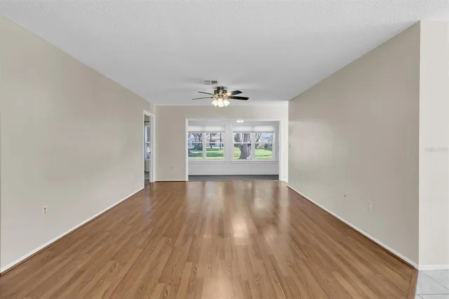 a view of an empty room with a window and wooden floor
