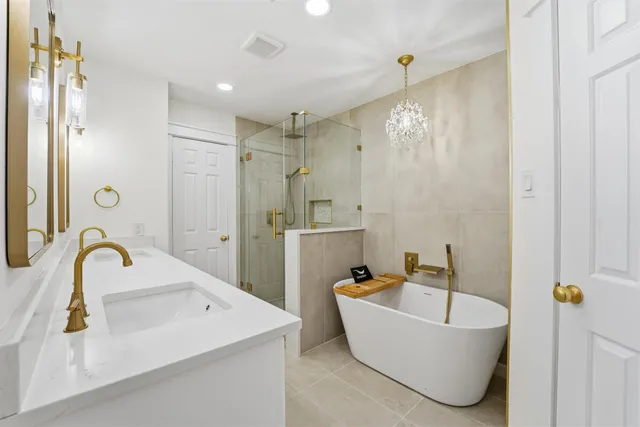 a bathroom with a tub a sink a mirror and a shower