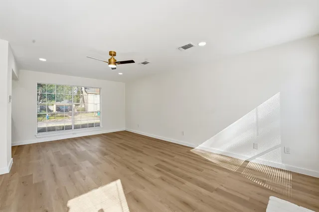 an empty room with wooden floor and windows
