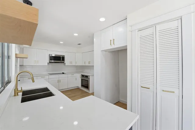 a kitchen with stainless steel appliances a refrigerator sink and white cabinets