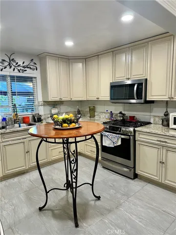 a kitchen with stainless steel appliances granite countertop a stove a sink dishwasher and a refrigerator with wooden cabinets