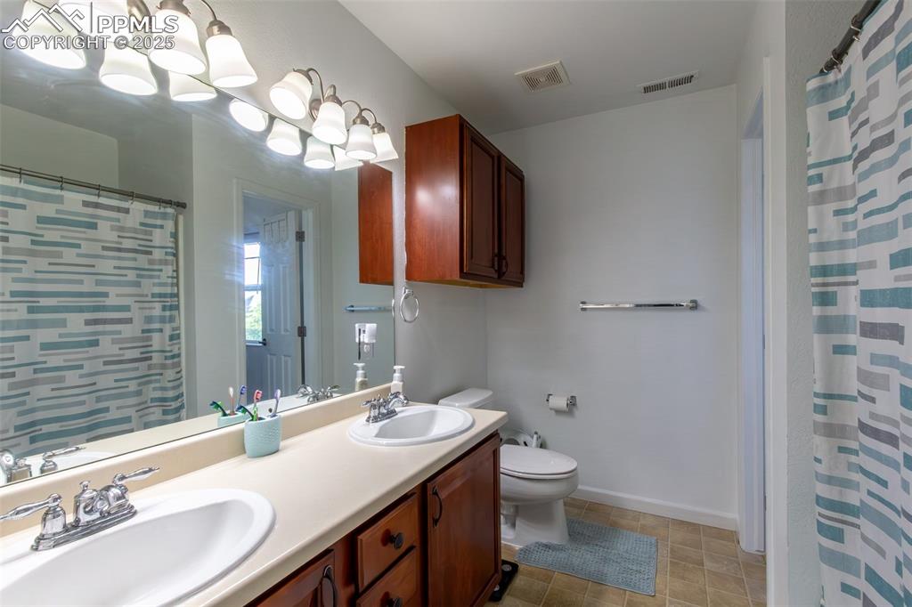 7544 Jaoul Point Peyton, CO 80831 - Photo 30 of 37 a bathroom with a granite countertop sink a toilet and a mirror