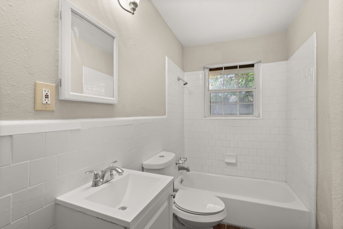 3031 Friar Point Road Houston, TX 77051 - Photo 7 of 15 First bathroom features light countertops and cabinets, custom paint, shower/tub combo with tile surround, mirror, tile floors, sleek fixtures and modern finishes, plenty of space to accommodate any visiting family or guests.