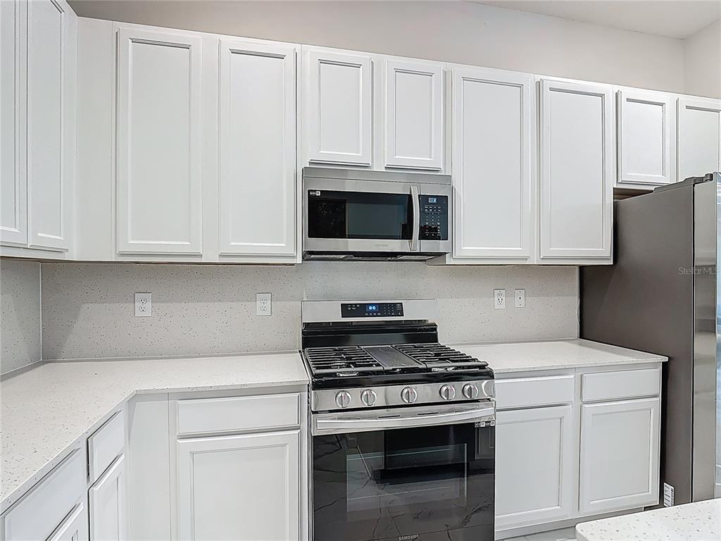 1326 Butterfly Orchid Road Davenport, FL 33837 - Photo 11 of 54 a kitchen with white cabinets and stainless steel appliances