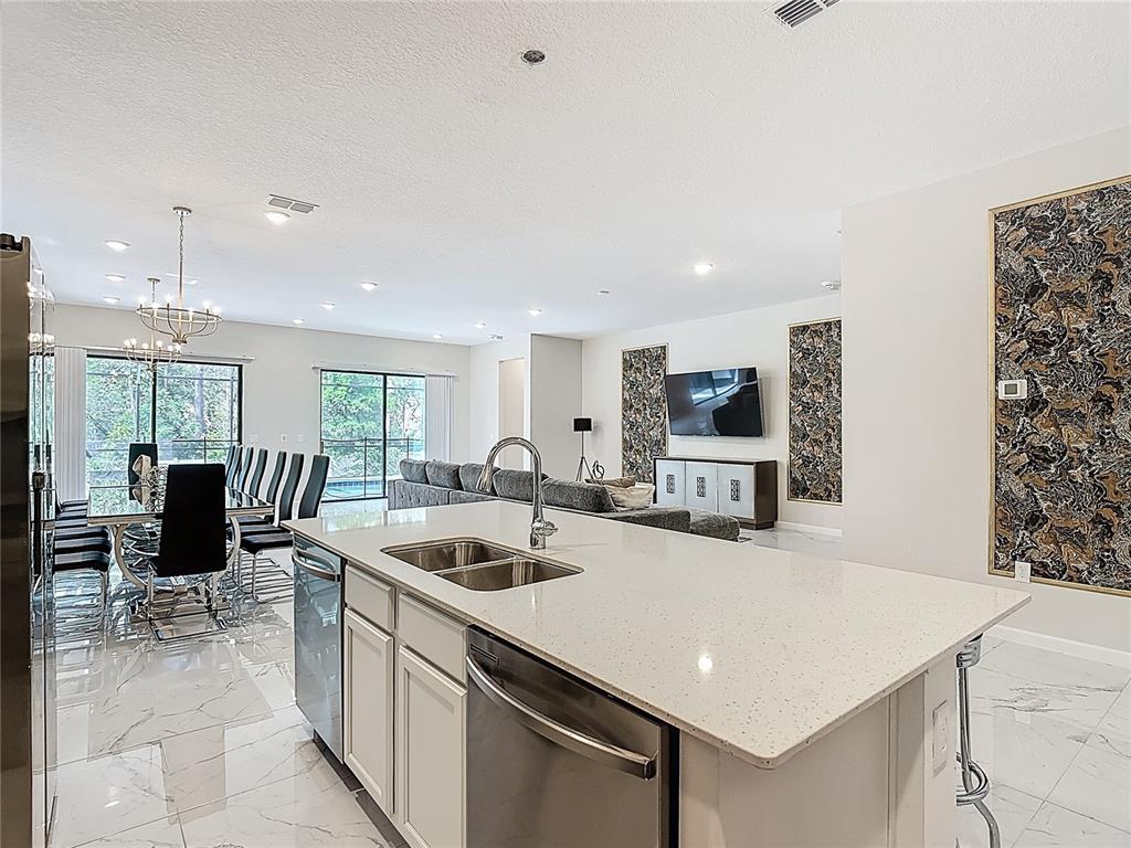 1326 Butterfly Orchid Road Davenport, FL 33837 - Photo 15 of 54 a kitchen with stainless steel appliances a stove a sink a oven a dining table and chairs