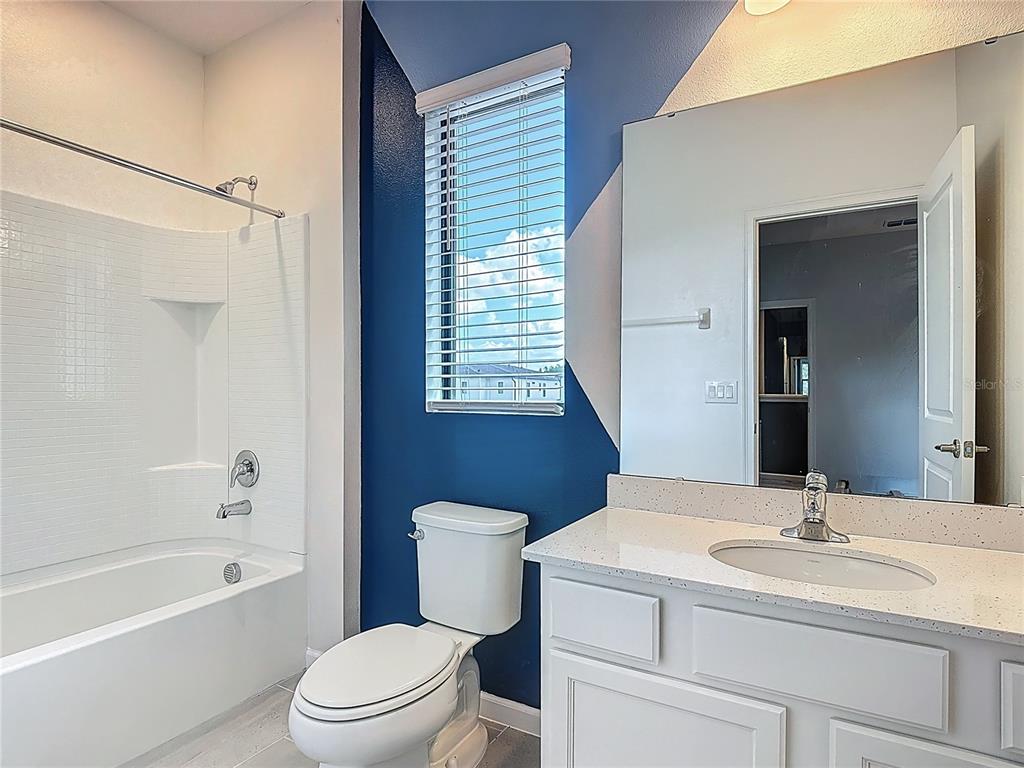 1326 Butterfly Orchid Road Davenport, FL 33837 - Photo 24 of 54 a bathroom with a sink a toilet a mirror a vanity and shower