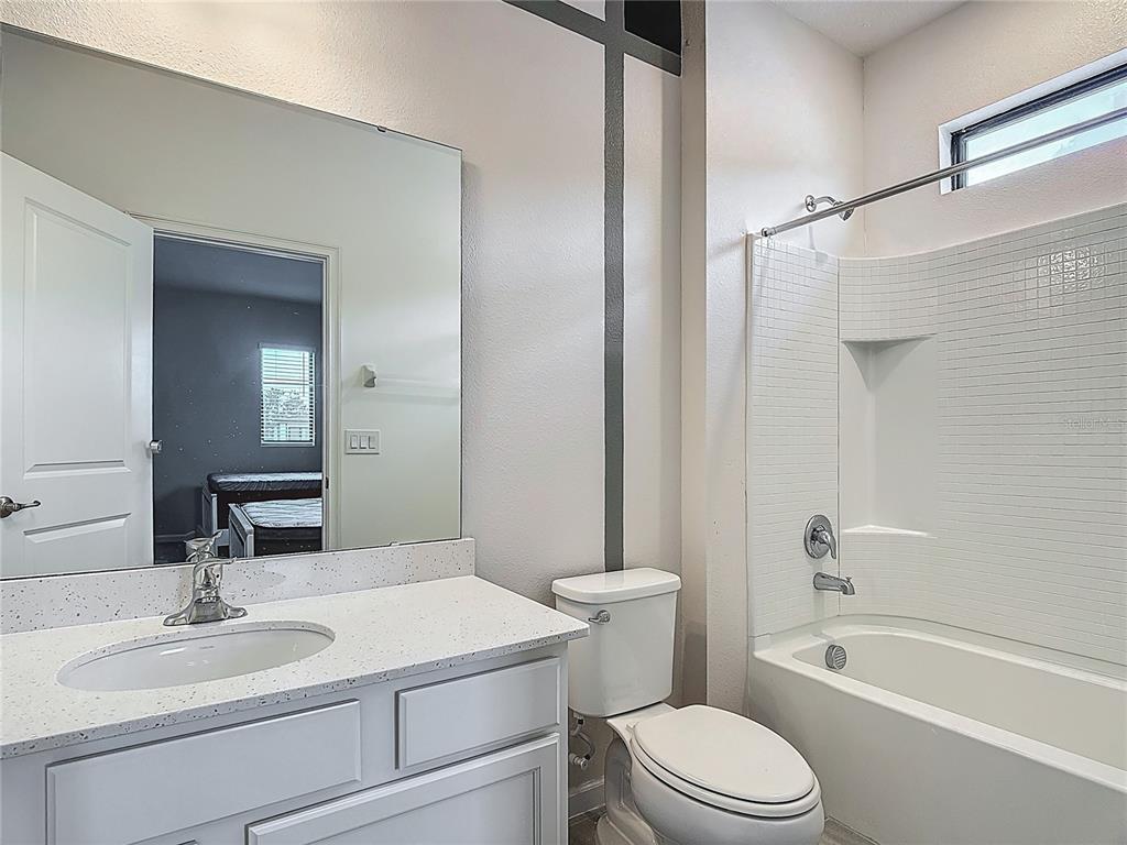 1326 Butterfly Orchid Road Davenport, FL 33837 - Photo 25 of 54 a bathroom with a granite countertop sink toilet a mirror and shower