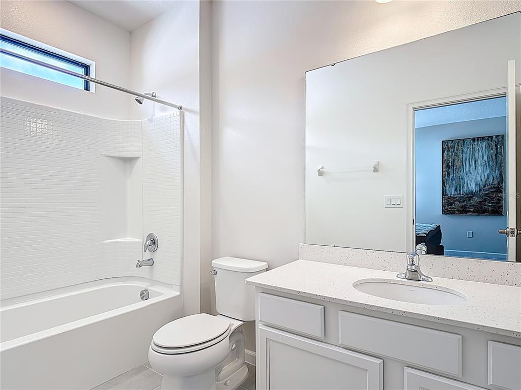 1326 Butterfly Orchid Road Davenport, FL 33837 - Photo 37 of 54 a bathroom with a granite countertop sink a toilet and a bathtub