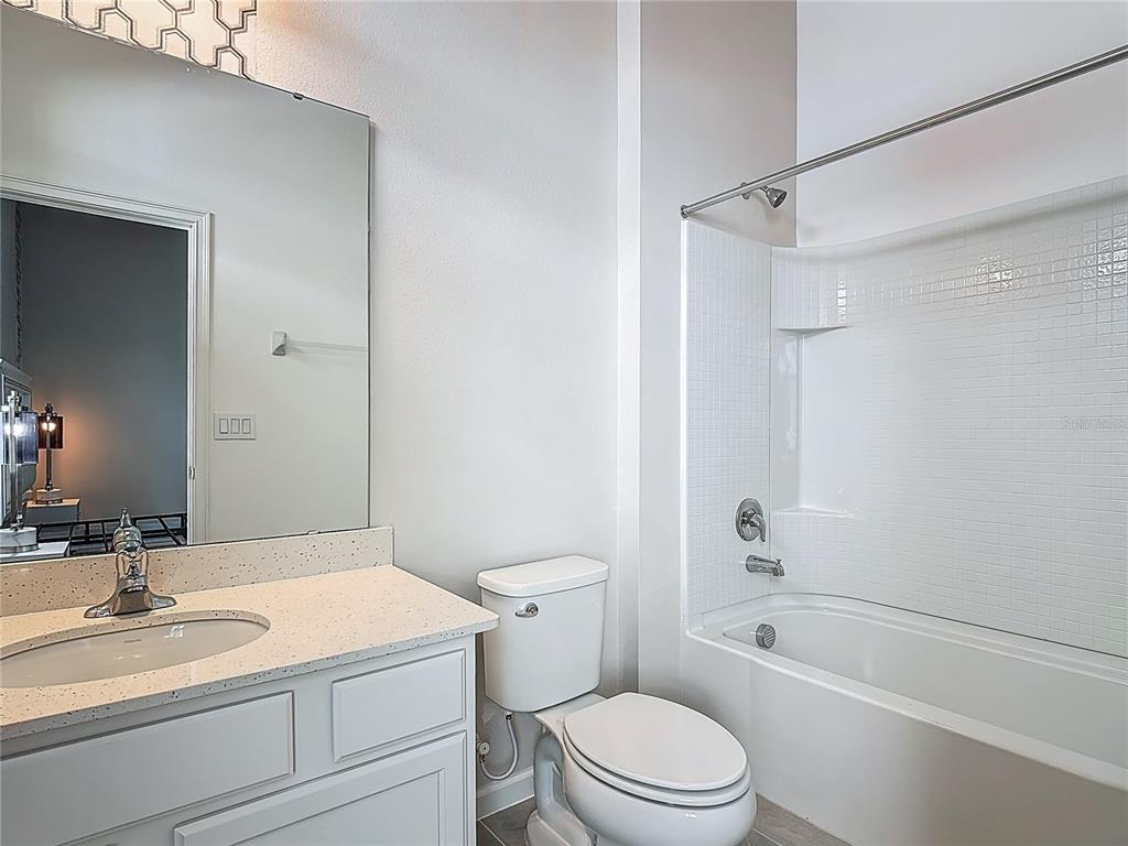 1326 Butterfly Orchid Road Davenport, FL 33837 - Photo 43 of 54 a bathroom with a granite countertop sink toilet a mirror and shower