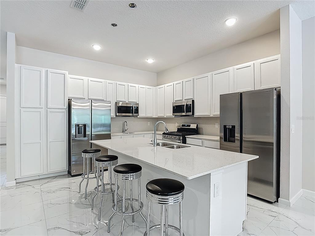 1326 Butterfly Orchid Road Davenport, FL 33837 - Photo 10 of 54 a kitchen with stainless steel appliances a refrigerator stove microwave and cabinets