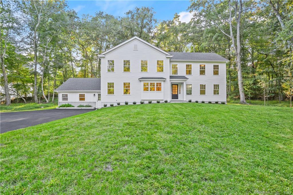 a front view of a house with a garden and trees